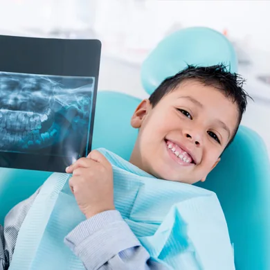 A young patient holding a dental X-ray image